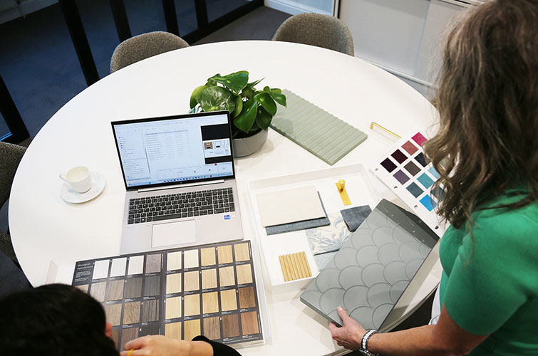 Interior designer reviewing material samples, finishes, and colour schemes at a table as part of the bespoke furniture and interior design process.