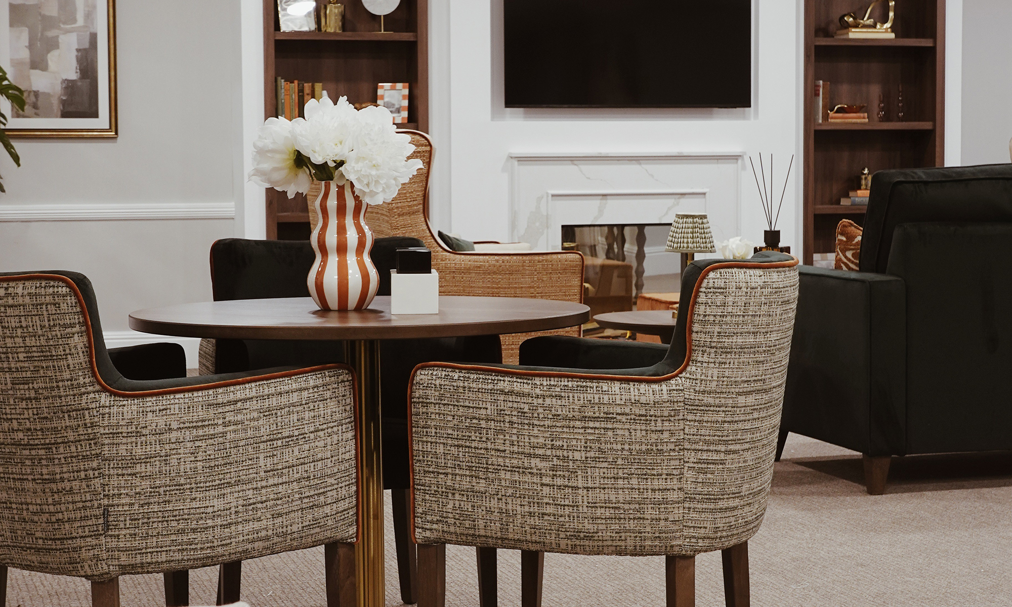 Lounge arrangement at Purley Gardens showing Shackletons upholstered Horsham tub chairs around a table, styled with warm tones and soft lighting.