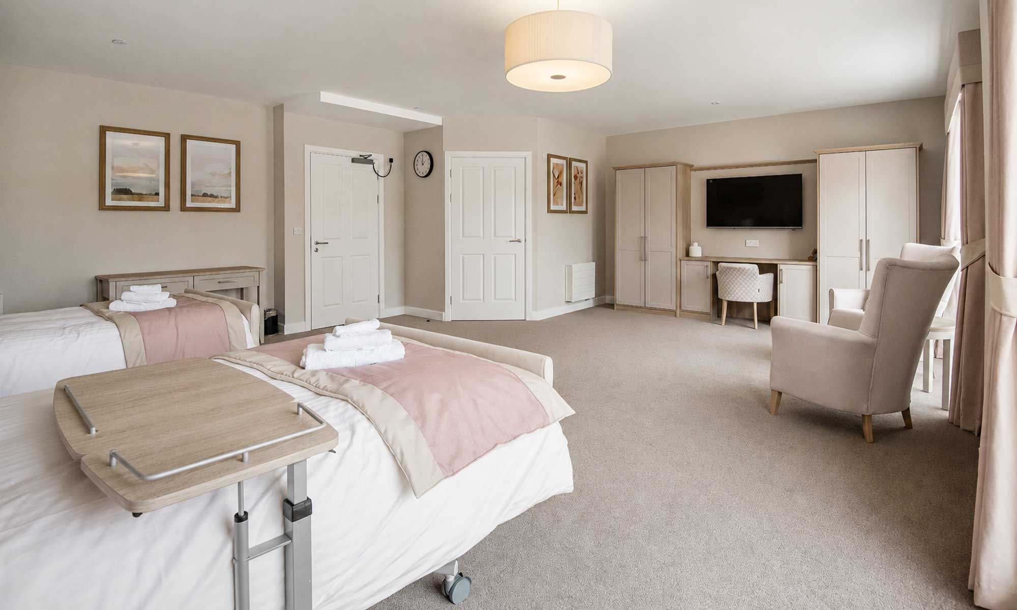 Twin care home bedroom at Bellerose Manor with bespoke fitted wardrobes, dressing table, overbed table and upholstered seating by Shackletons.